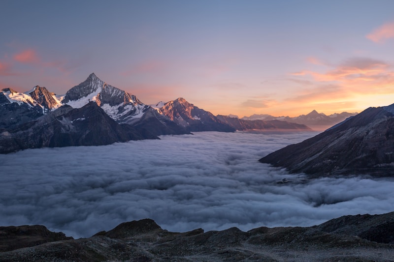 Snowy mountain peaks rising above a sea of clouds at sunrise