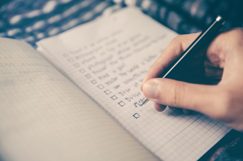 Hand writing a checklist with a pen in a grid-paper notebook